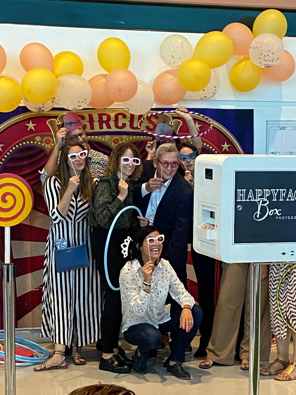 Groupe de visiteurs posant au photobooth dans le décor de cirque